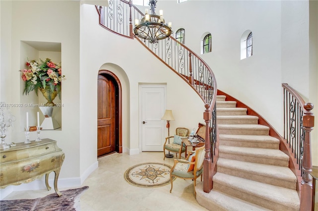 stairway with a notable chandelier and a towering ceiling