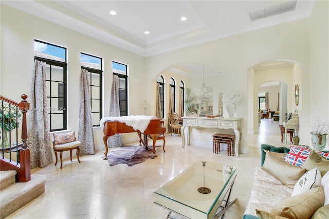 interior space featuring a raised ceiling, ornamental molding, a towering ceiling, and an inviting chandelier