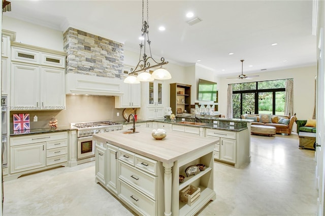 kitchen featuring pendant lighting, a kitchen island with sink, crown molding, ceiling fan, and appliances with stainless steel finishes