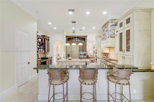 kitchen featuring a kitchen breakfast bar, kitchen peninsula, hanging light fixtures, and cream cabinetry