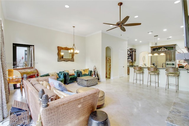 living room with ceiling fan with notable chandelier and crown molding