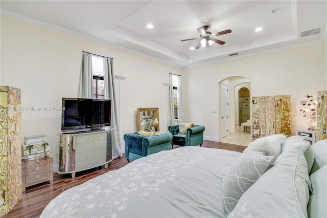 bedroom featuring hardwood / wood-style flooring, crown molding, ceiling fan, and a tray ceiling