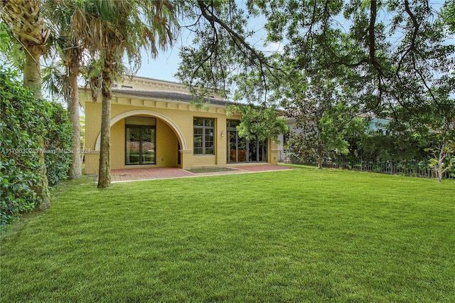 rear view of property with a patio and a lawn