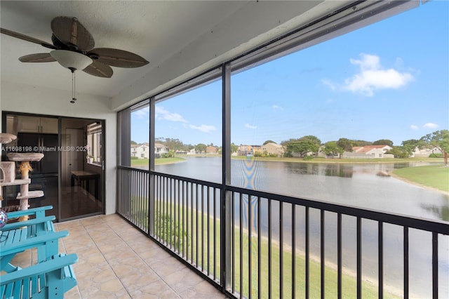 unfurnished sunroom featuring ceiling fan and a water view