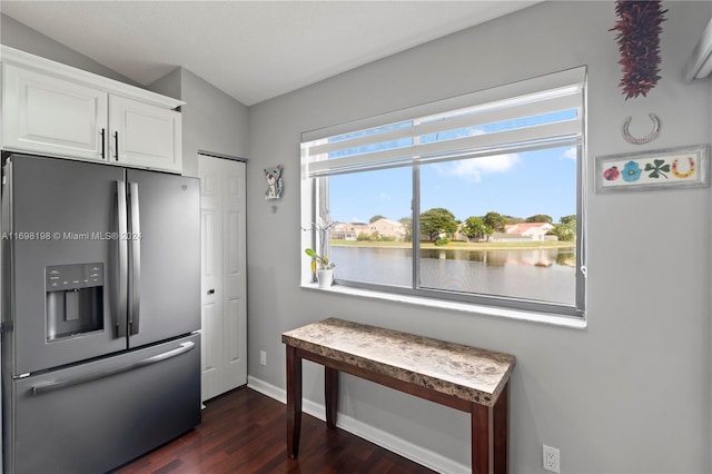 kitchen featuring white cabinets, a water view, vaulted ceiling, dark hardwood / wood-style floors, and stainless steel fridge