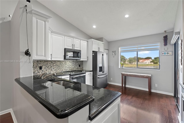 kitchen featuring kitchen peninsula, appliances with stainless steel finishes, dark hardwood / wood-style flooring, vaulted ceiling, and white cabinets