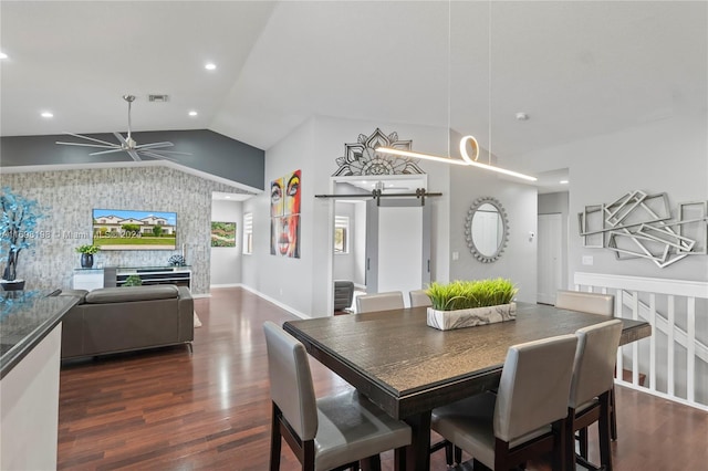 dining room with dark hardwood / wood-style flooring, a barn door, ceiling fan, and lofted ceiling