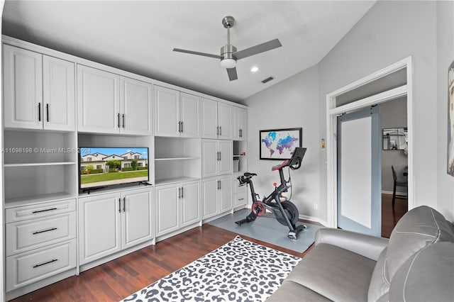 exercise room featuring dark hardwood / wood-style flooring, vaulted ceiling, and ceiling fan