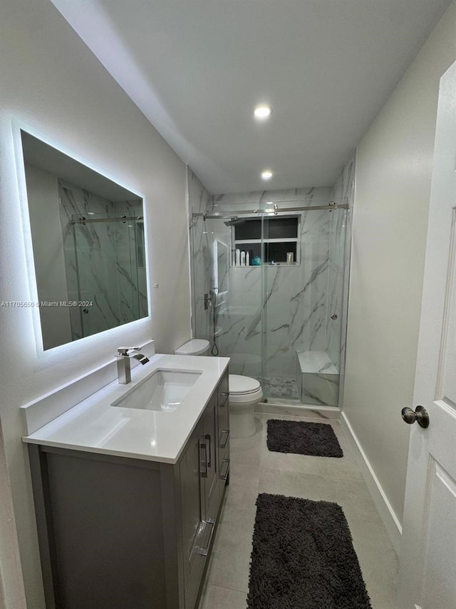 bathroom featuring tile patterned flooring, vanity, toilet, and a shower with door