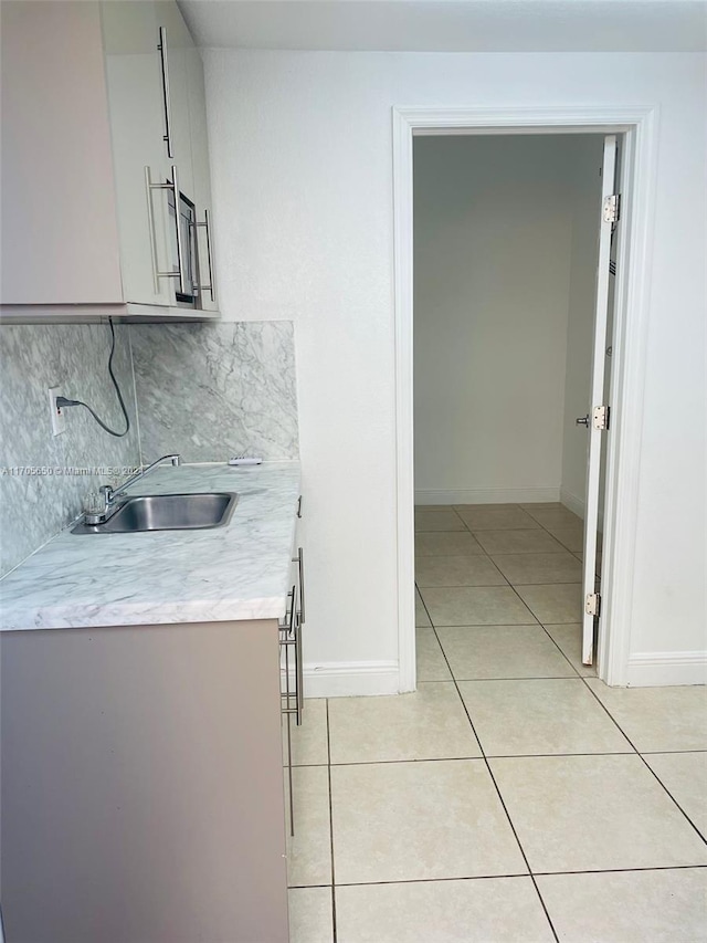 kitchen with white cabinets, decorative backsplash, sink, and light tile patterned floors