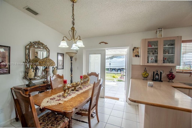 tiled dining area featuring a textured ceiling and a notable chandelier