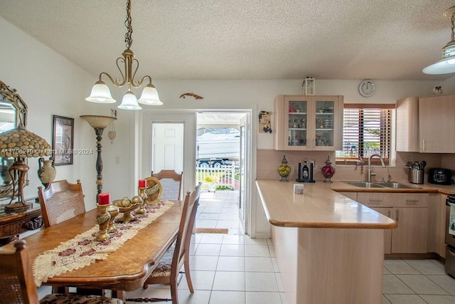 kitchen featuring sink, light brown cabinetry, decorative light fixtures, light tile patterned flooring, and kitchen peninsula