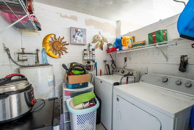 washroom with washer and clothes dryer, wooden walls, and water heater