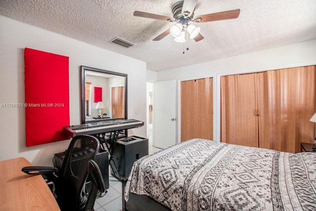 tiled bedroom featuring a textured ceiling, two closets, and ceiling fan