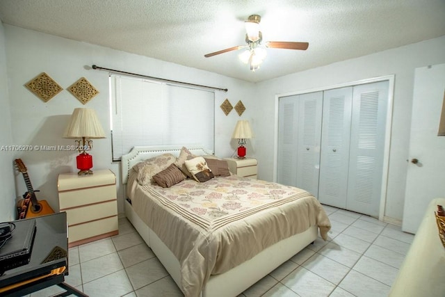 bedroom with ceiling fan, light tile patterned flooring, a textured ceiling, and a closet