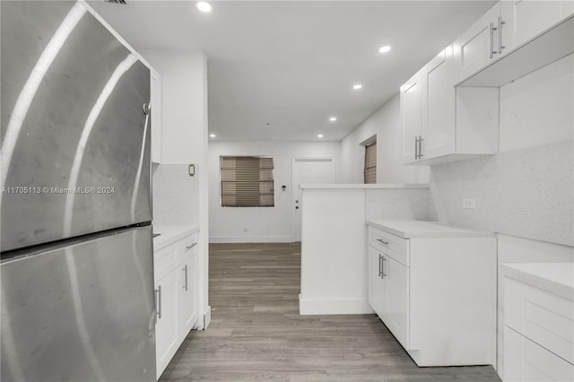 kitchen featuring backsplash, stainless steel refrigerator, white cabinetry, and light wood-type flooring