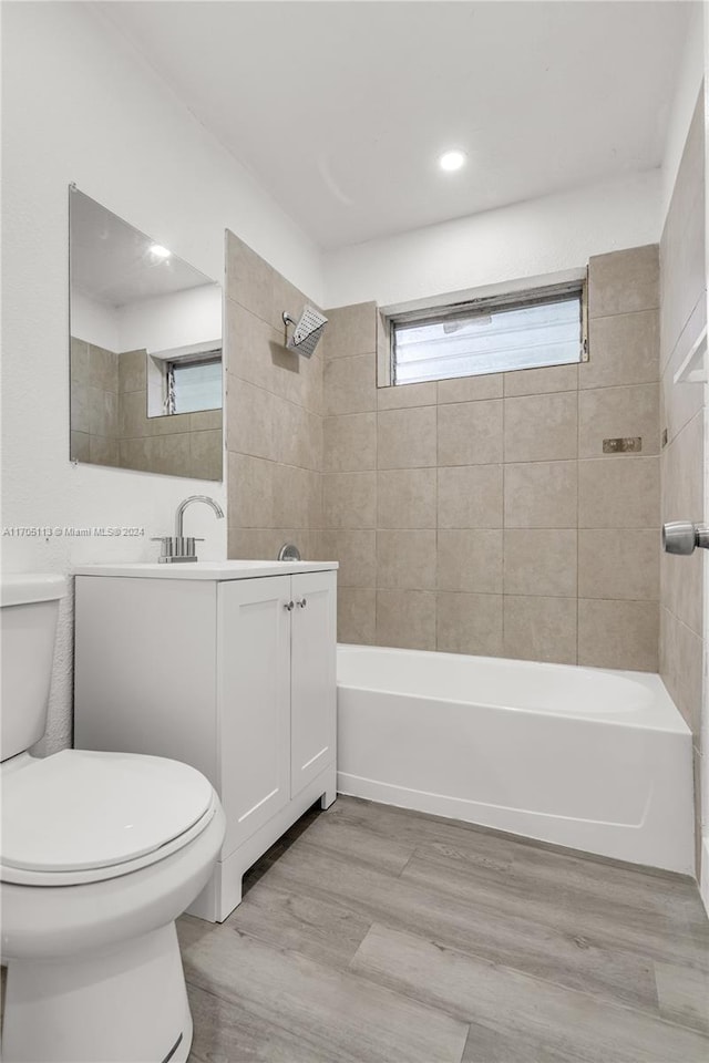 full bathroom with vanity, wood-type flooring, tiled shower / bath combo, and toilet