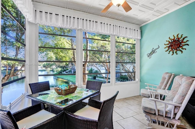 sunroom with ceiling fan and a water view