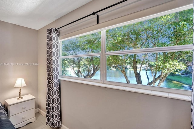 unfurnished bedroom with a textured ceiling, a water view, and multiple windows