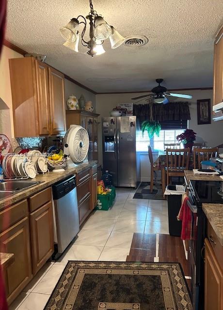 kitchen featuring a textured ceiling, light tile patterned flooring, stainless steel appliances, and ceiling fan with notable chandelier