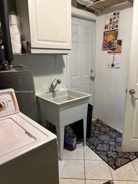 laundry area featuring light tile patterned flooring, cabinets, electric water heater, and washer / clothes dryer