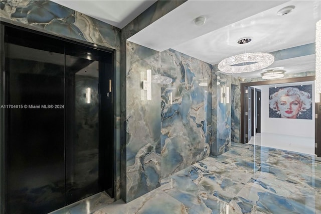 hallway with tile walls and an inviting chandelier