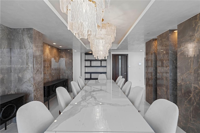 dining room with a notable chandelier and tile walls