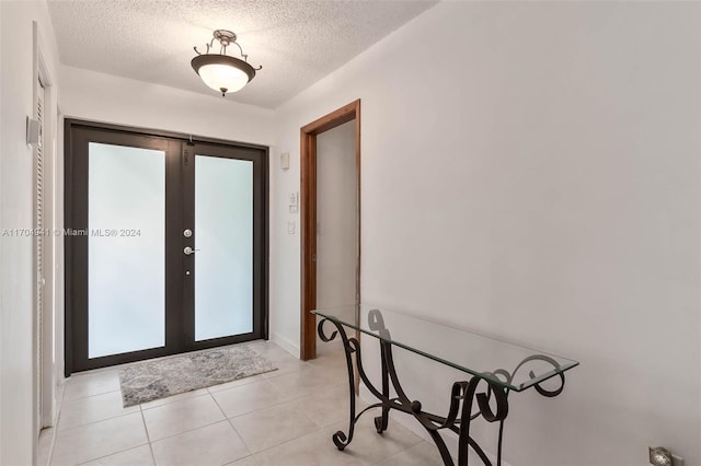 entryway featuring french doors, a textured ceiling, and light tile patterned floors