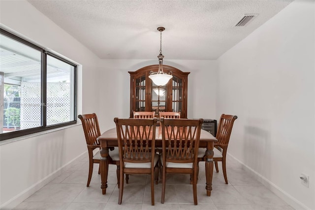 tiled dining room featuring a textured ceiling