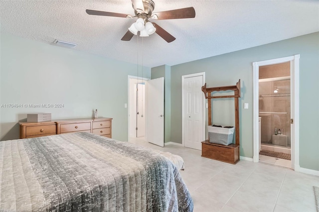 bedroom featuring ensuite bathroom, a textured ceiling, ceiling fan, a closet, and light tile patterned flooring