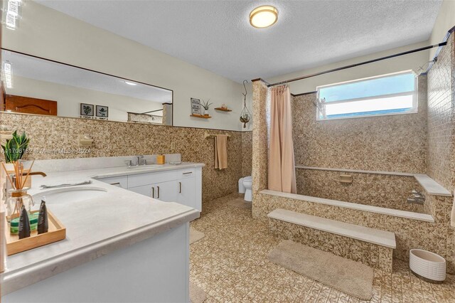 50 SW 130th Ave, Miami, FL 33184 - full bathroom featuring a textured ceiling, vanity, shower / bathtub combination with curtain, tile walls, and toilet