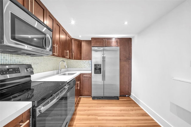 kitchen with appliances with stainless steel finishes, light hardwood / wood-style floors, tasteful backsplash, and sink