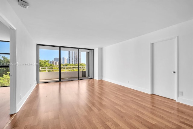 empty room featuring floor to ceiling windows and light hardwood / wood-style floors