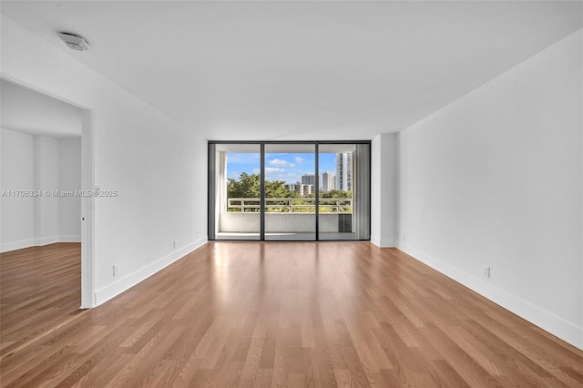 unfurnished room featuring expansive windows and light hardwood / wood-style floors