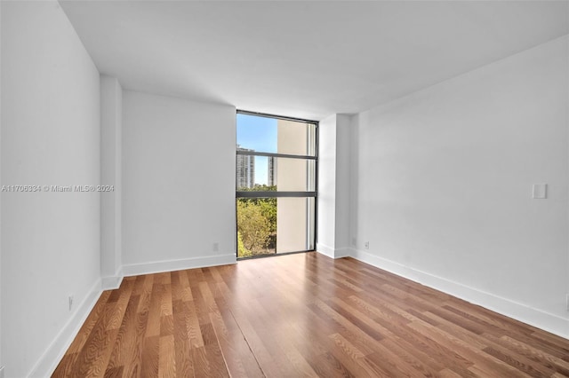 spare room with wood-type flooring and a wall of windows