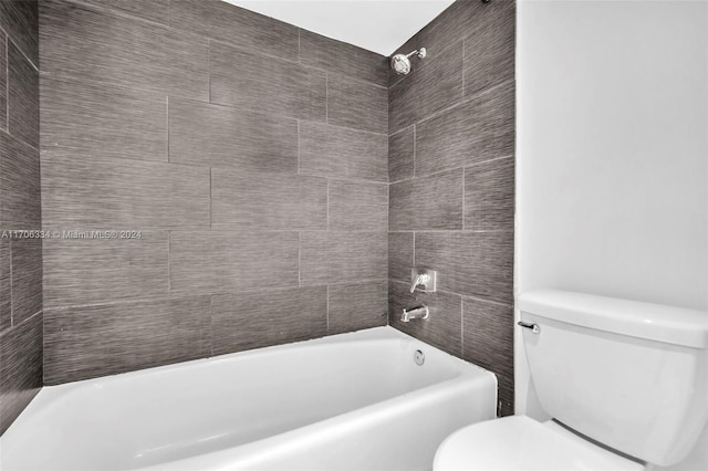 bathroom with tiled shower / bath combo and toilet