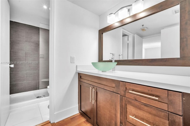 bathroom with a shower, toilet, vanity, and hardwood / wood-style flooring