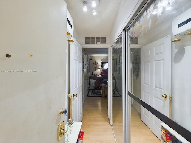 hall with an AC wall unit and light wood-type flooring