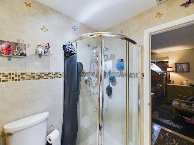 bathroom with toilet, tile walls, and an enclosed shower