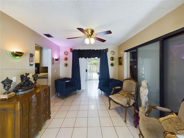 living room with ceiling fan, a textured ceiling, and light tile patterned flooring