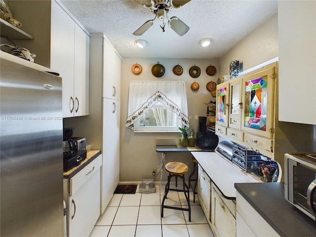 kitchen with ceiling fan, white cabinetry, a textured ceiling, stainless steel appliances, and light tile patterned floors