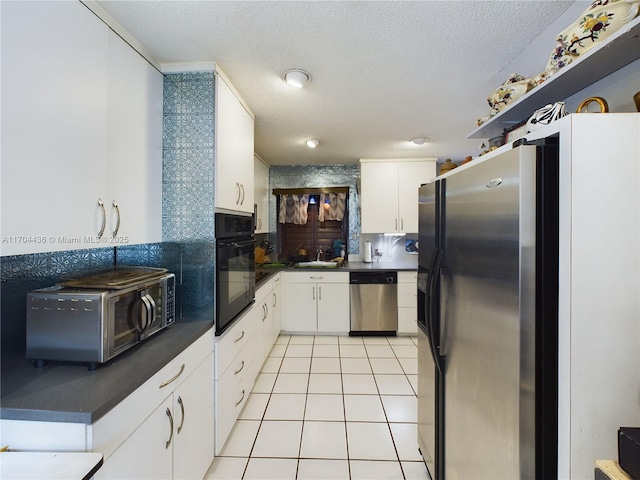 kitchen featuring a textured ceiling, white cabinetry, stainless steel appliances, sink, and light tile patterned floors