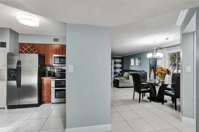 kitchen with backsplash, a textured ceiling, decorative light fixtures, light tile patterned floors, and appliances with stainless steel finishes