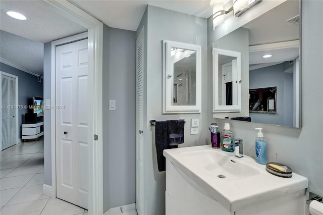 bathroom with tile patterned flooring, vanity, ornamental molding, and a textured ceiling