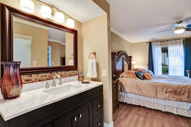 bedroom featuring crown molding, sink, light hardwood / wood-style flooring, ceiling fan, and a textured ceiling