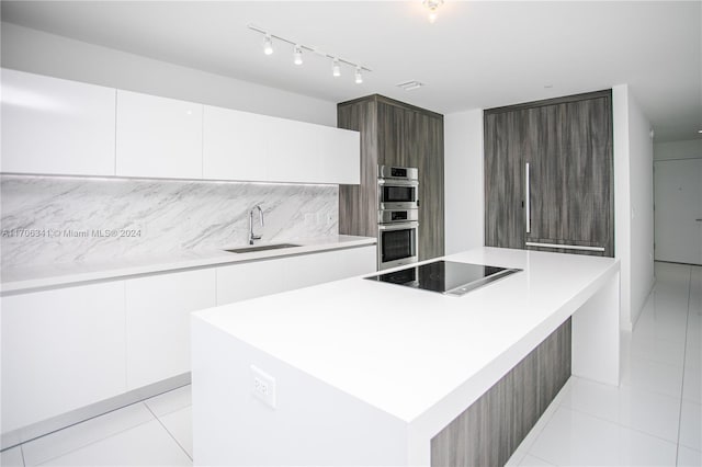 kitchen with black electric stovetop, sink, white cabinets, and a kitchen island