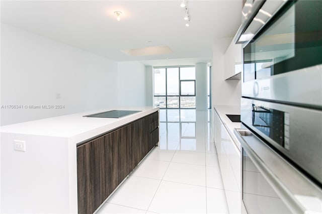 kitchen featuring a center island, stainless steel double oven, black electric cooktop, dark brown cabinets, and light tile patterned floors