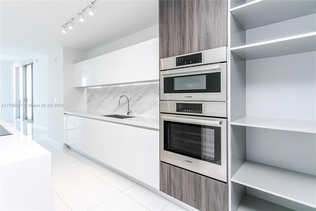 kitchen with white cabinetry, sink, light tile patterned floors, and stainless steel double oven