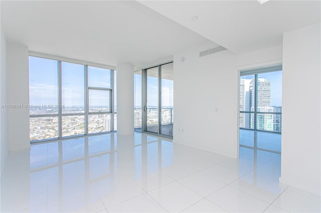 tiled empty room featuring a wall of windows