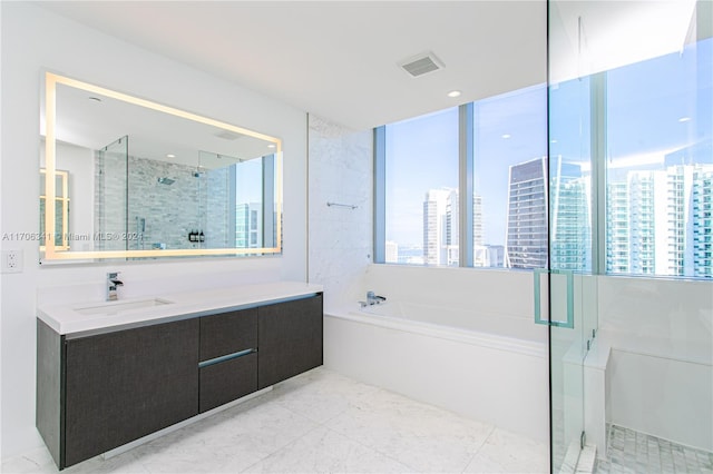 bathroom with vanity and shower with separate bathtub